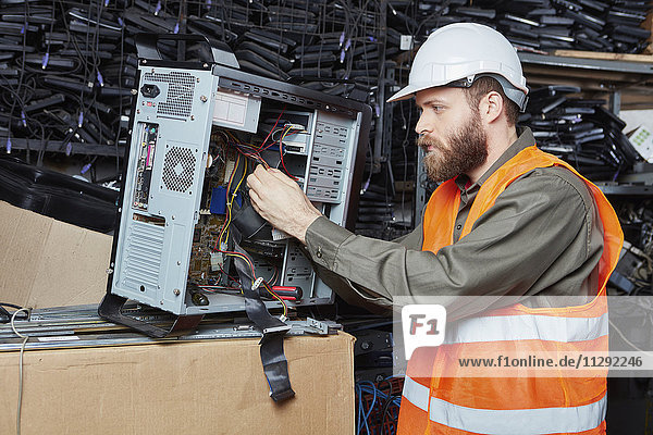 Worker in computer recycling plant dismounting desktop pc