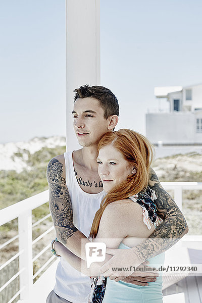 Glückliches junges Paar auf einer Terrasse des Strandhauses mit Blick auf das Meer