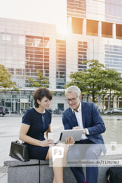 Geschäftsmann und Geschäftsfrau mit digitalem Tablett im Freien