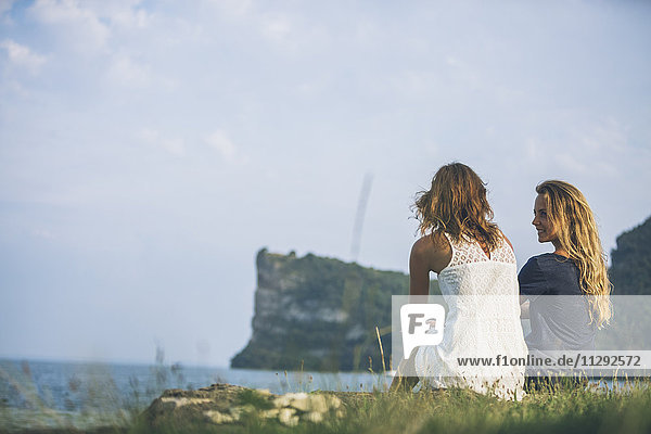 Italien  Gardasee  zwei junge Frauen sitzen am Seeufer
