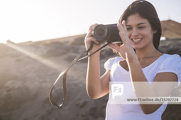 Junge Frau am Strand beim Fotografieren