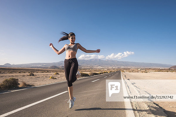 Sportive young woman jumping on a road