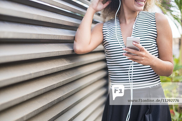 Junge Frau mit Smartphone Musik hören  Teilansicht