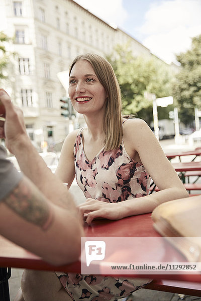 Lächelnde Frau  die den Mann in einem Straßencafé ansieht.