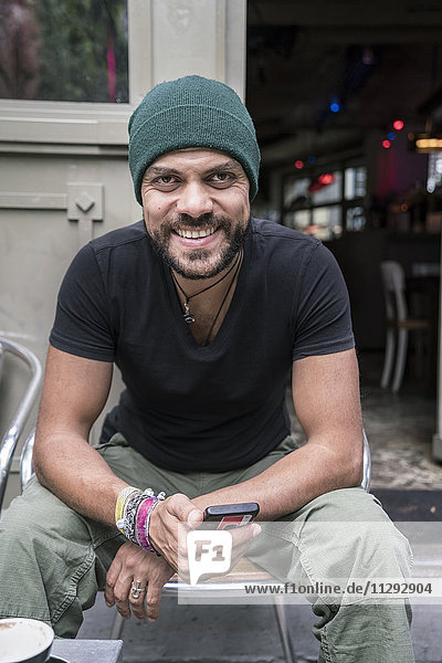 Deutschland  Berlin  Porträt eines lächelnden Mannes vor dem Coffee-Shop