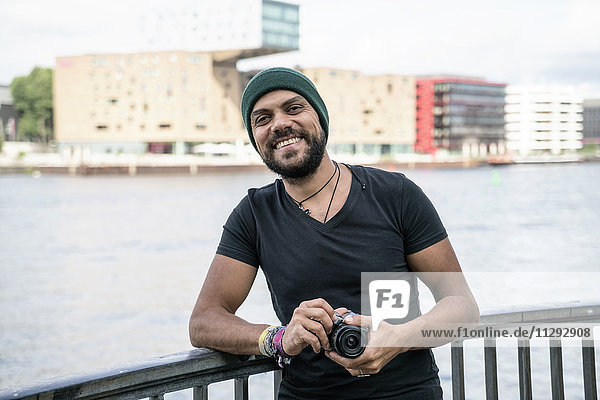 Deutschland  Berlin  Portrait eines glücklichen Mannes mit Kamera
