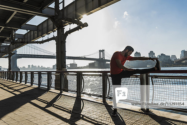 USA  New York City  sportive man stretching at East River