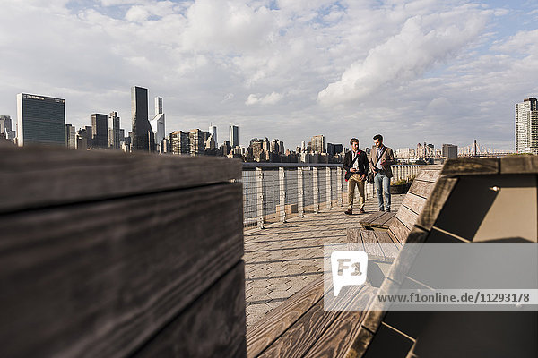 USA  New York City  two businessmen walking along East River