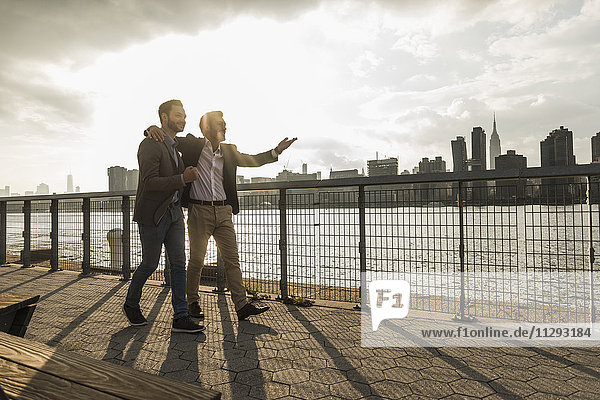 USA  New York City  zwei Geschäftsleute  die gemeinsam am East River entlang gehen.