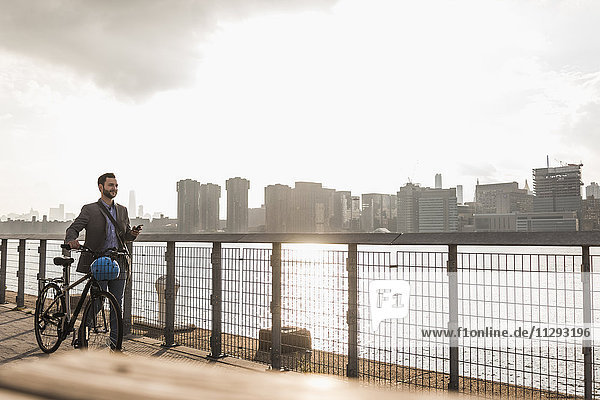 USA  New York City  Geschäftsmann mit Fahrrad entlang des East River