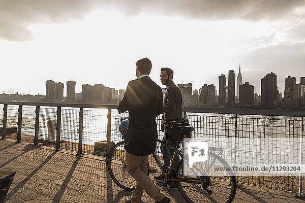 USA  New York City  zwei Geschäftsleute mit Fahrrad entlang des East River
