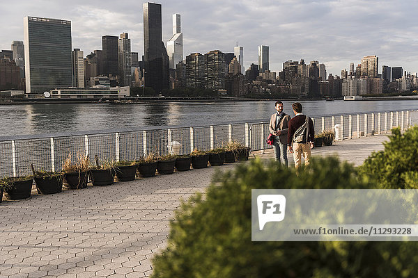 USA  New York City  zwei junge Männer im Gespräch am East River