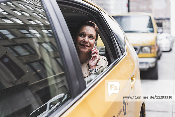 USA  New York City  lächelnde Frau im Taxi am Handy