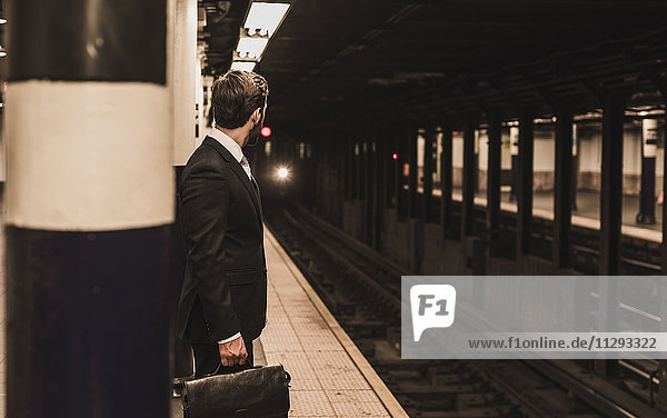 Junger Geschäftsmann wartet am Bahnsteig der U-Bahn-Station