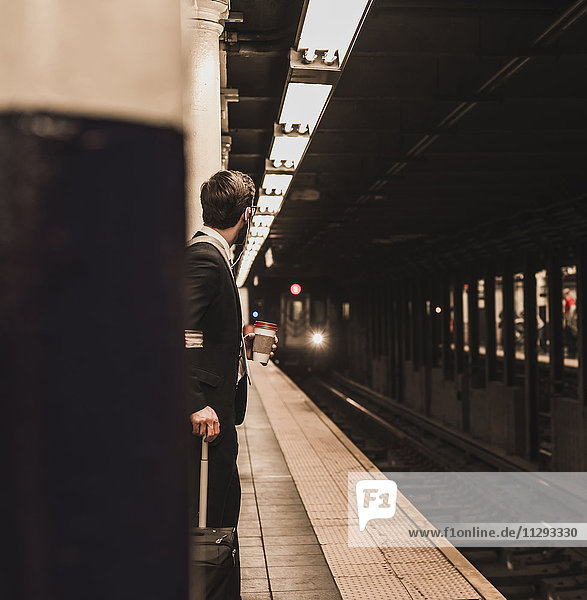 Junger Geschäftsmann wartet am Bahnsteig der U-Bahn-Station