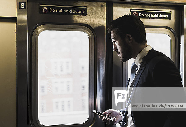 Junge Geschäftsleute mit der U-Bahn  mit dem Smartphone