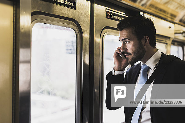 Young businessman taking metro  using smart phone