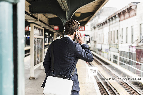 Young businessman waiting at metro station platform  using smart phone