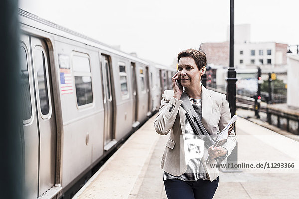 Reife Frau mit Smartphone am S-Bahnhof