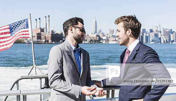 USA  New York City  zwei Geschäftsleute im Gespräch auf der Fähre auf dem East River