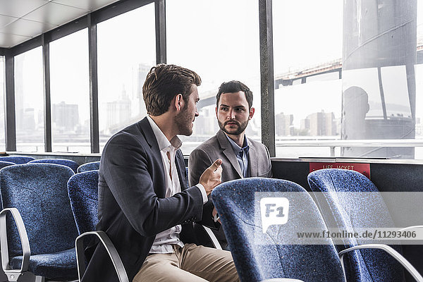 Two businessmen talking on passenger deck of a ferry