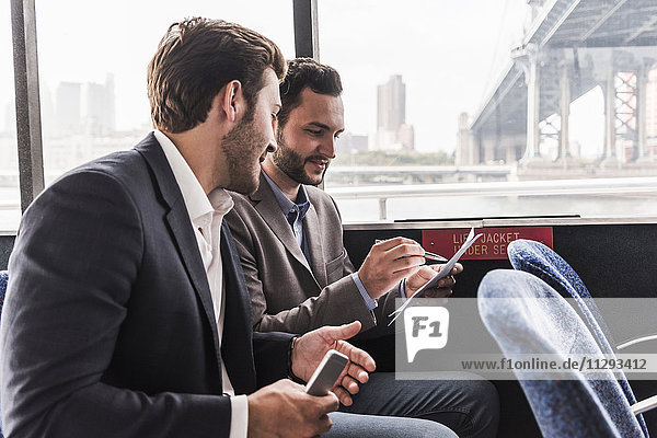 Two businessmen with document talking on passenger deck of a ferry