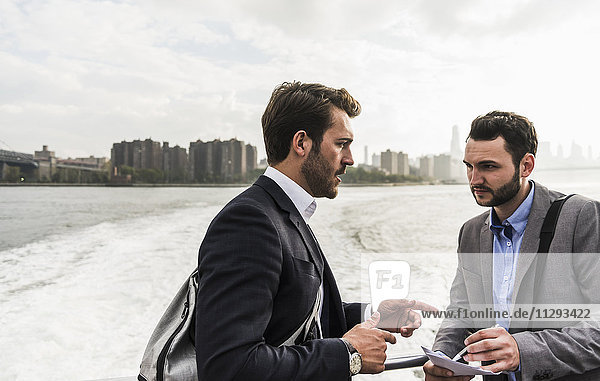 USA  New York City  two businessmen talking on ferry on East River