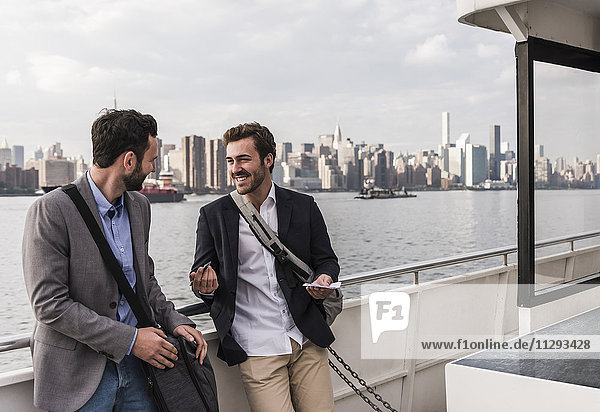 USA  New York City  zwei lächelnde Geschäftsleute im Gespräch auf der Fähre auf dem East River