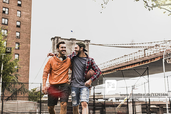 USA  New York  zwei glückliche junge Männer auf einem Outdoor-Basketballplatz