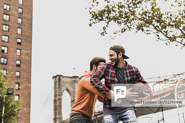 USA  New York  two young men with basketball having fun on an outdoor court