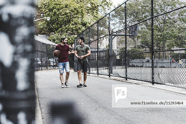 Zwei Freunde  die mit Basketball im Freien spazieren gehen.