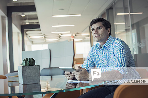 Geschäftsmann im Büro sitzend  mit digitalem Tablett