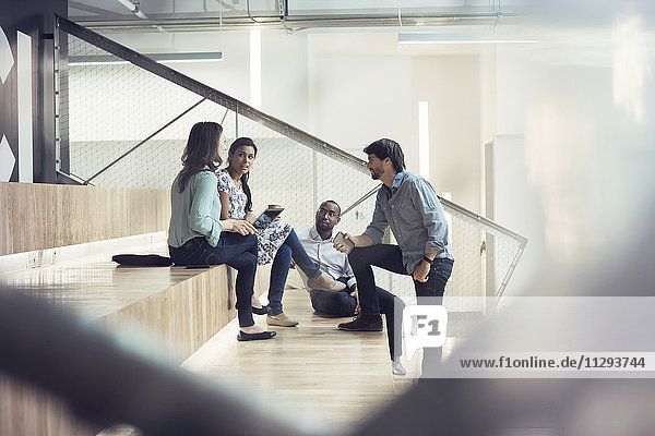 Young business people discussing  sitting on stairs