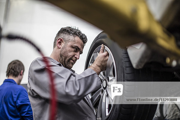 Kfz-Mechaniker in einer Werkstatt beim Reifenwechsel