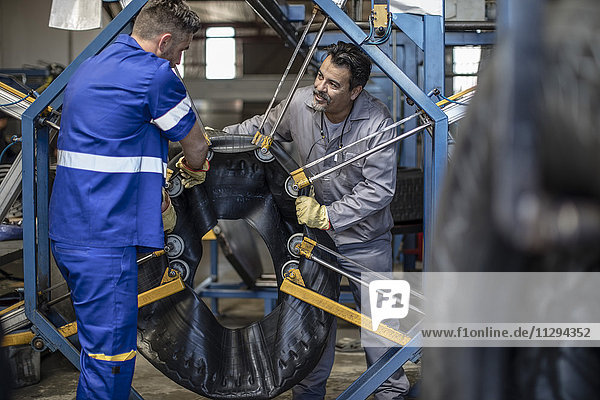 Two tire repairmen working together in factory