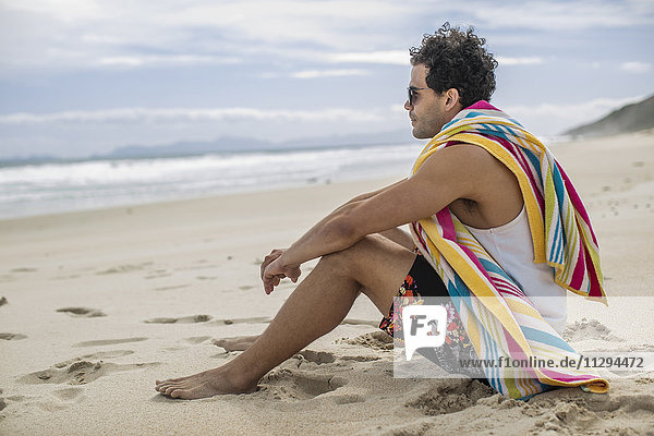 Junger Mann am Strand sitzend