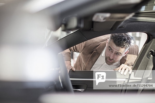 Man looking into car in car dealership