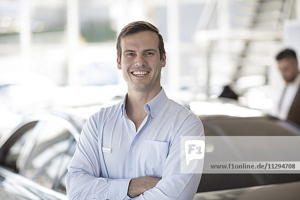 Portrait of smiling car dealer in showroom