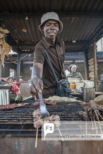 Ein Verkäufer grillt Fleisch an einem Straßenstand  Straßenszene  Bamenda  Region Nord-West  Kamerun  Afrika