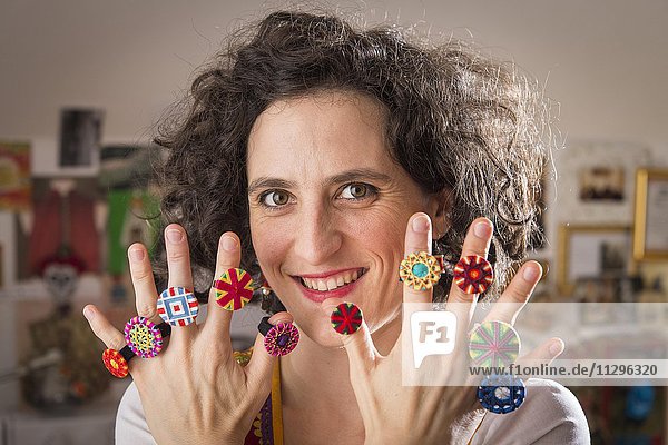 Button maker  young woman with her fingers displaying selection of ten Posamentenknopf rings  Ichenhausen  Bavaria  Germany  Europe