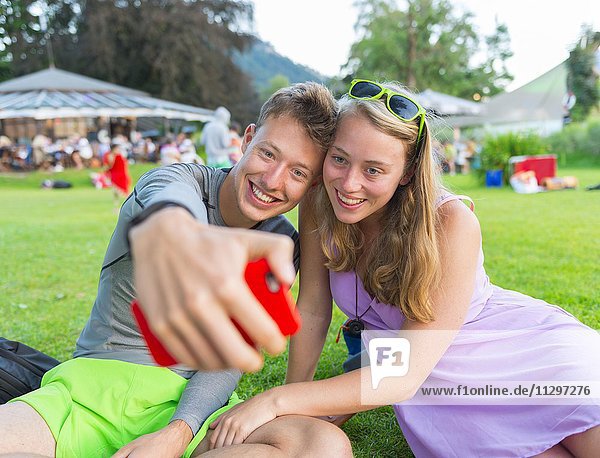 Junger Mann und junge Frau lächelt fotografiert sich mit einem Handy selbst Selfie Bayern Deutschland Europa
