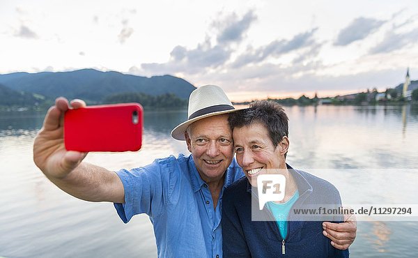 Mann und Frau lächelt  fotografiert sich mit einem Handy selbst  Selfie  Schliersee  Oberbayern  Bayern  Deutschland  Europa