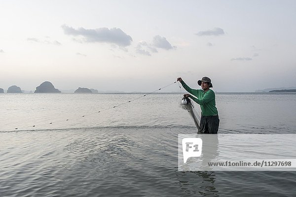 Fischer steht im Wasser und fischt mit Netz  Tubkaek Beach  Krabi  Thailand  Asien