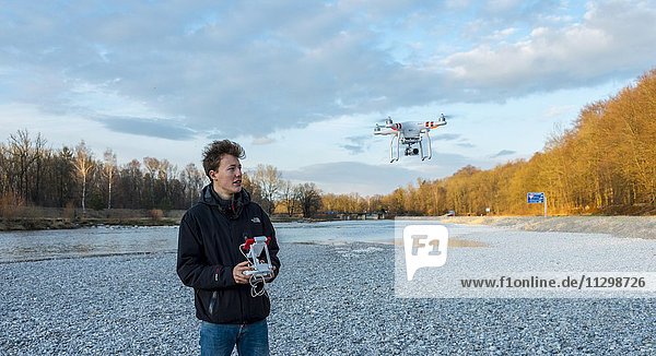 Junger Mann steuert einen Quadrocopter  Drohne mit Kamera fliegt  DJI Phantom 3  München  Oberbayern  Bayern  Deutschland  Europa