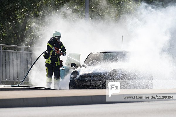 Feuerwehrmann löscht brennendes Auto  Deutschland  Europa