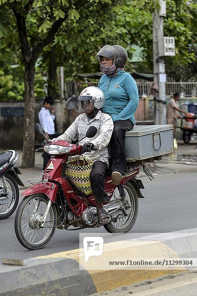 Mann mit Moped und Frau sitzend auf einer Kiste  Phnom Penh  Kambodscha  Asien