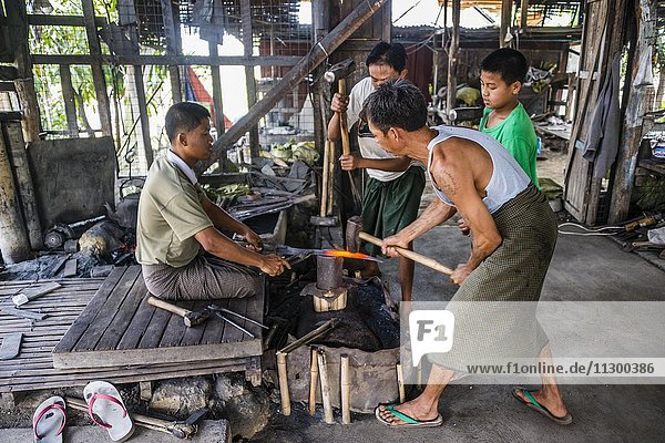 Einheimische Männer hämmern mit Hammern auf glühendes Metallstück  Schmied  Schmiede  Inle Lake  Inle See  Shan Staat  Myanmar  Asien