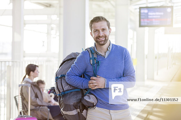 Portrait lächelnder Mann mit Rucksack am Flughafen