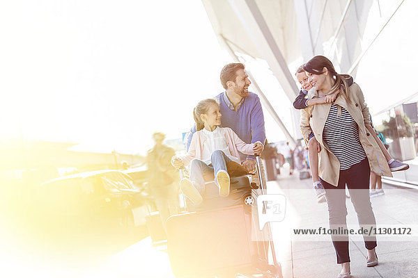 Familienwanderung mit Gepäckwagen außerhalb des Flughafens