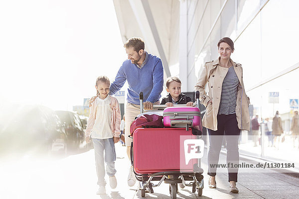 Familie mit Gepäckwagen außerhalb des Flughafens